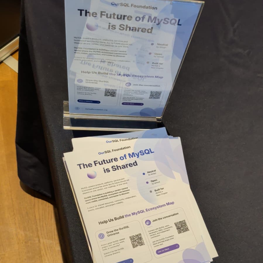 Flyers reading 'The Future of MySQL is Shared' stacked on the booth table, with QR codes to suggest a resource and join the Slack.